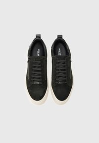 Sneaker in suede nero con suole in gomma bianca, design con lacci e dettagli con cerniere ai lati. Lacci piatti e suole interne imbottite.
