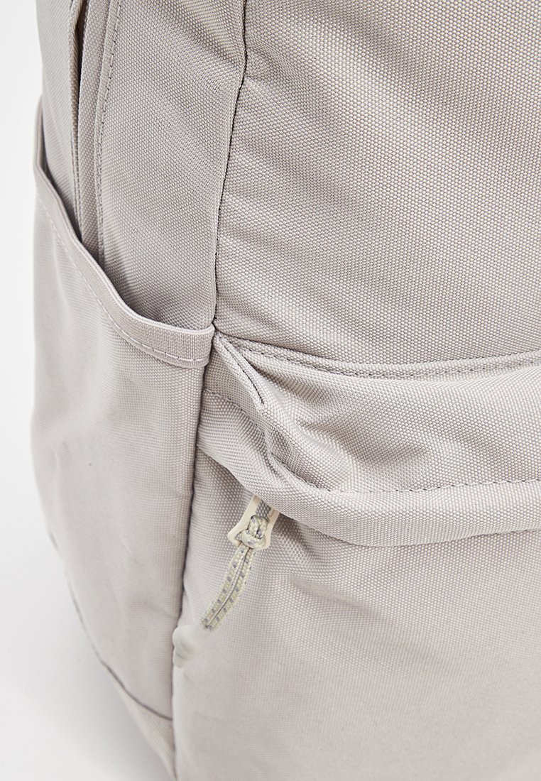 Grijze stoffen rugzak met een gestructureerd oppervlak, zijvakken en een ritssluiting compartiment voor opslag.