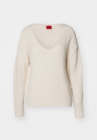 Crème gebreide trui met een diepe V-hals, verlaagde schouders en geribde zoom. Gemaakt van een textiel met een ontspannen pasvorm. Voorzien van een klein rood label.