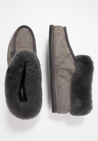 Zapatillas de ante gris con forro de piel sintética gris oscuro y suela resistente. Tienen una forma redondeada y un detalle de borde en contraste.