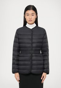 Svart polstret jakke med knappelukking, rund hals og beltedetalj. Jevn tekstur med horisontalt quiltet design.
