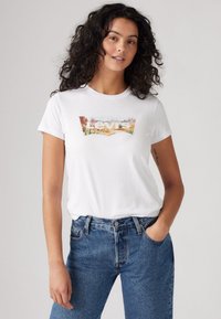 Witte katoenen t-shirt met een kleurrijke Levi's logo grafiek. Gecombineerd met hooggetailleerde blauwe jeans. Casual pasvorm, korte mouwen.