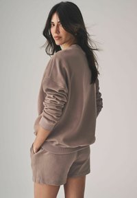 Fleece-tröja och shorts-set i dämpad taupe, med s�änkt axelsöm och ribbade ärmslut, samt fickor på shortsen. Mjuk textur.