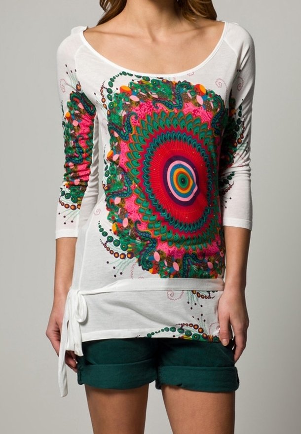 Vit långärmad skjorta med ett färgglatt cirkulärt mönster i rosa, grönt och blått; har en sidoknytning. Matchas med mörkgröna shorts.