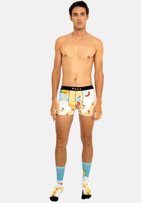 Boxers pour hommes en bleu clair avec des motifs vibrants de surfeurs et de thèmes tropicaux. Dotés d'une ceinture noire avec le logo "WAXX".