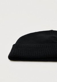 Μαύρος πλεκτός σκούφος με διπλωμένη ρεβέρ. Διαθέτει ριγωτή υφή και λείο φινίρισμα στην κορυφή, κατάλληλος για κρύο καιρό.