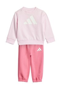 Un sweat-shirt rose et un pantalon de jogging assorti, fabriqués en tissu doux. Le sweat-shirt arbore le logo Adidas blanc ; le pantalon de jogging présente le logo sur la jambe gauche.