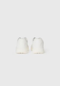 Pantofi sport albi cu un vârf din piele netedă, laturi texturate și o talpă groasă din cauciuc. Design minimalista fără logo-uri vizibile.