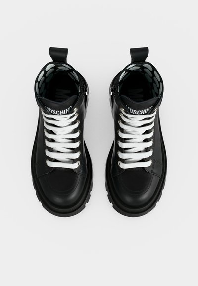 Ζευγάρι μαύρα δερμάτινα sneakers ψηλής κορυφής με λευκά κορδόνια, χοντρές σόλες, λουράκια για τράβηγμα και εσωτερική επένδυση με σχέδια.