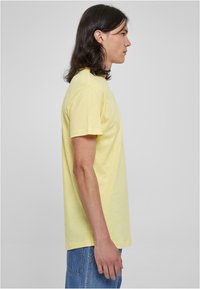 Gul kortærmet t-shirt i en afslappet pasform, lavet af blødt stof, med et enkelt design og en rund halsudskæring, båret med blå jeans.