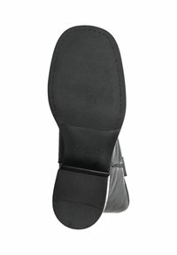 Semelle de botte noire en cuir à la cheville avec un motif en caoutchouc texturé et un léger talon. Présente une surface lisse et un accent de marque sur le côté.