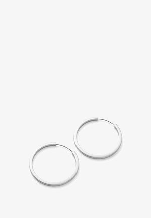 Par de pendientes de aro lisos de plata con cierres de alambre delgado sobre un fondo blanco.
