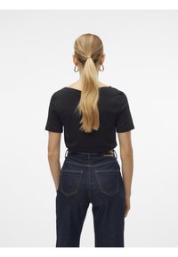 Czarna bluzka z krótkim rękawem i szerokim dekoltem, zestawiona z wysokim stanem ciemnych jeansów z tylnymi kieszeniami i kontrastującym przeszyciem.