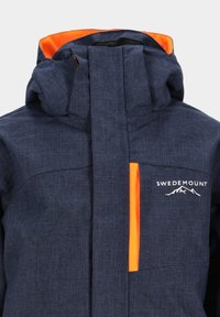 Marineblaue Jacke aus strukturiertem Stoff mit orangefarbenem Innenfutter. Verfügt über einen hohen Kragen, ein Logo auf der Brust und einen Reißverschluss.