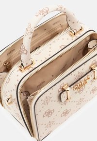 Borsa di pelle crema con hardware dorato, logo in rilievo e design a motivi. Presenta scomparti doppi e una maniglia rotonda.