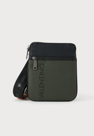 Bolsa Valentino em materiais verde escuro e preto, com fecho de correr e alça ajustável, apresentando um logótipo proeminente na frente.