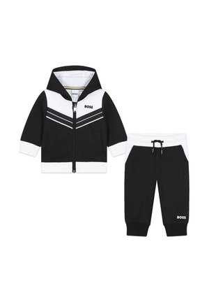 Ensemble de survêtement pour enfants en noir et blanc, comprenant une veste à capuche zippée avec un motif rayé et un pantalon fuselé assorti avec cordon de serrage.