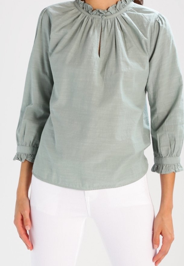 Light green cotton blouse with a gathered neckline, keyhole opening, and three-quarter sleeves featuring ruffled cuffs.