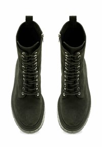 Botas de tobillo de ante negro con un diseño de cordones, ojales plateados y una cremallera lateral, que presentan una suela texturizada para mayor tracción.