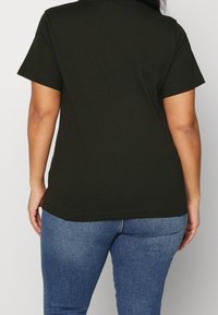 Mörkgrön t-shirt med kort ärm och rund halsringning. Tillverkad av bomull. Slät textur, något figursydd design, fåll vid höften.