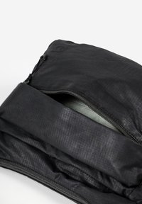 Borsa o sacchetto in tessuto nero con texture, parzialmente aperta, che mostra la fodera interna grigio chiaro, su uno sfondo bianco.