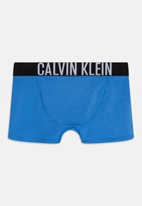 Blauwe katoenen boxershorts met een zwarte elastische tailleband met witte "CALVIN KLEIN" letters. Glad oppervlak en aansluitend ontwerp.