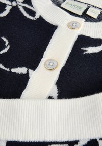 Cardigan blu navy con motivo floreale bianco, colletto e orlo a costine bianchi, dotato di due bottoni rotondi con una delicata finitura dorata.