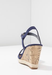 Tmavě modré wedge sandály s korkovým podpatkem, syntetickým svrškem a řemínkem na kotníku. Vlastnosti zahrnují jutu obtočenou kolem základny podpatku.