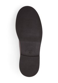 Schwarze Schuhsohle mit einer strukturierten Oberfläche und abgerundeter Form, umrandet von einer glatten Kante und einem kleinen Etikett.