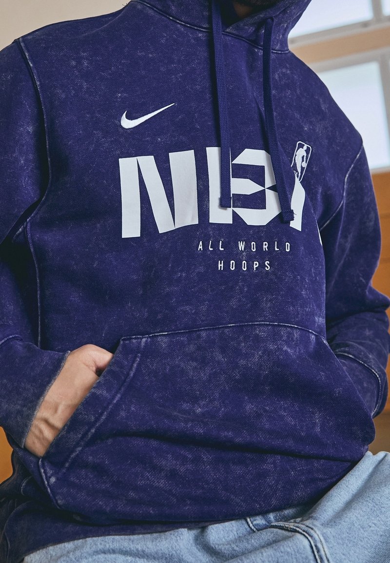 Sweat à capuche violet en tissu doux, avec une poche kangourou, un logo Nike blanc et un graphisme NBA "ALL WORLD HOOPS".