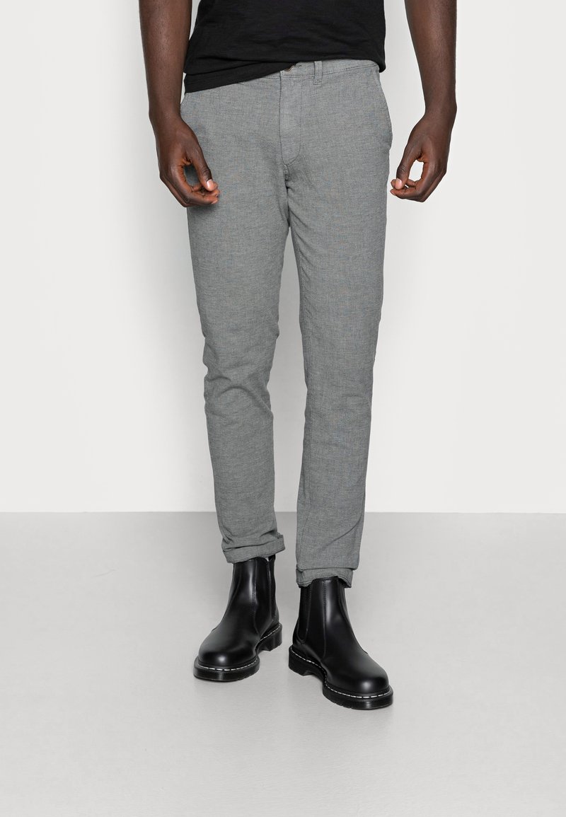 Grå texturerade byxor med slim fit, med uppvikta nederkanter och sidofickor, i kombination med svarta ankelboots.