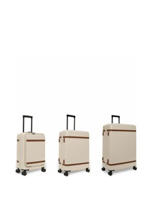 Drei beige Hartschalenkoffer mit braunen Akzenten und schwarzen Teleskopgriffen, von klein bis groß angeordnet, jeweils mit vier Spinner-Rädern.