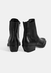 Bottines noires en cuir avec un petit talon, dotées de coutures verticales et de fermetures éclair sur les côtés pour un enfilage facile. Fini lisse et design épuré.
