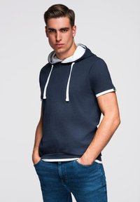 Námořnická mikina s krátkým rukávem, bílými šňůrkami a vnitřním límcem, kombinovaná s modrými džíny; směs bavlny, volný střih, hladká textura.