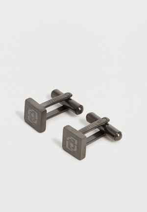 Para ciemnych metalowych kwadratowych spinków do mankietów z wygrawerowanym logo i napisem "S. STEEL" na zatrzasku, przedstawiona na białym tle.