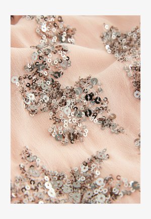 Jasnoróżowa tkanina ozdobiona metalicznymi cekinami, tworzącymi skomplikowane wzory i tekstury w całym materiale.
