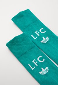 Turkise treningusokker med hvit "LFC" tekst og Adidas-logo, laget av strukturert strikket stoff og ribbede mansjetter.