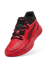 Roter Sportschuh mit strukturierter Oberseite, schwarzen Schnürsenkeln und dezenten Logos. Verfügt über eine geformte Ferse und eine flexible Gummisohle für guten Halt.