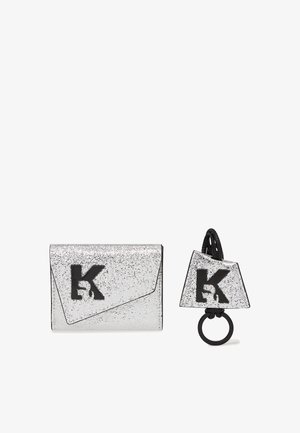 Clutch prateado brilhante com logotipo e acabamento pretos, apresentando um design de aba angulada. Inclui um porta-chaves correspondente em forma triangular.