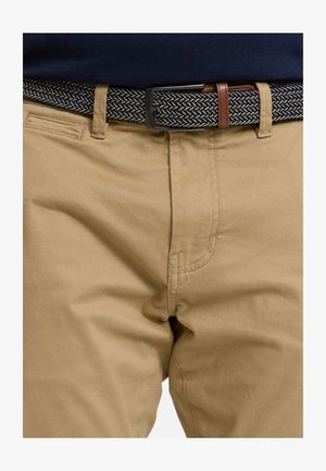 Kaki broek met een gladde textuur, voorzien van een klassiek ontwerp en voorzakken. Gecombineerd met een zwart-wit geweven riem met patroon.