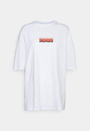 T-shirt blanche en coton, avec un graphique rectangulaire portant l'inscription "ACCROCHE-TOI À TES RÊVES" en texte rouge et noir. Manches courtes et coupe ample.