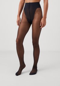 Schwarze, durchsichtige Ganzkörperstrumpfhose mit hoher Taille, gewelltem Saum und offener Zehenpartie. Glatte Textur, minimale Nähte und eine enganliegende Silhouette.