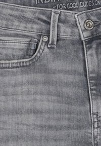 Grå denimjeans med en klassisk femfickdesign, knappstängning och sydda detaljer. Har subtila blekningar och en slät textur.