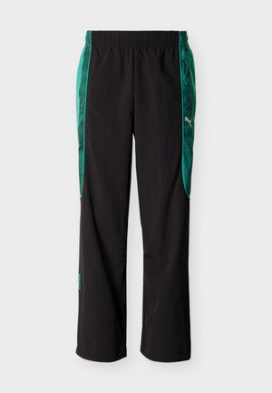 Mustad spordipüksid rohelise mustriga küljetahvlitega ja elastse vöökohaga, millel on paremal küljel valge Puma logo.