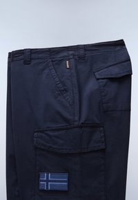 Mørkeblå cargobukser med flere lommer og en blå broderet flagpatch på den store sidelomme.