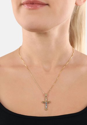Gros plan sur une personne portant un collier avec un pendentif croix en or, avec une figure en argent de Jésus sur une fine chaîne en or, sur un haut noir.