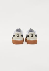 Sneaker in suede nera e grigia con suola in gomma naturale, dotate di linguetta e tallone bianchi, accento in oro con logo e dettagli laterali perforati.