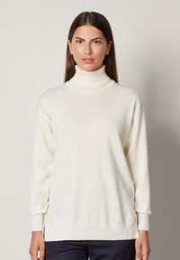 Weißer Rollkragenpullover aus weichem Material, mit lockerer Passform, gerippten Bündchen und Saum. Glatte Textur ohne sichtbare Muster.