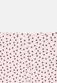 Lichtroze broek met een geribbelde textuur, voorzien van een patroon met donkerbruine stippen. Tailleband en stiksels zichtbaar aan de bovenkant.