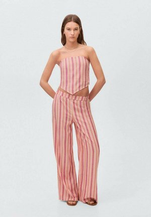 Bez naramenica, ružičasti prugasti crop top s šiljastim rubom uparen s odgovarajućim širokim hlačama. Tkanina ima horizontalne pruge različitih širina.